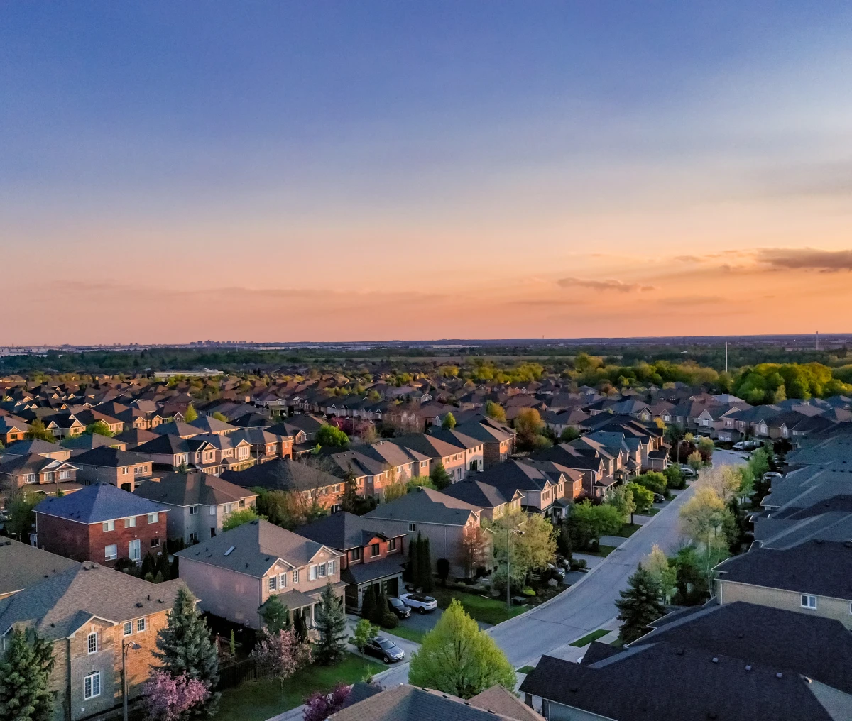 Suburban neighborhood at sunset with colorful sky.